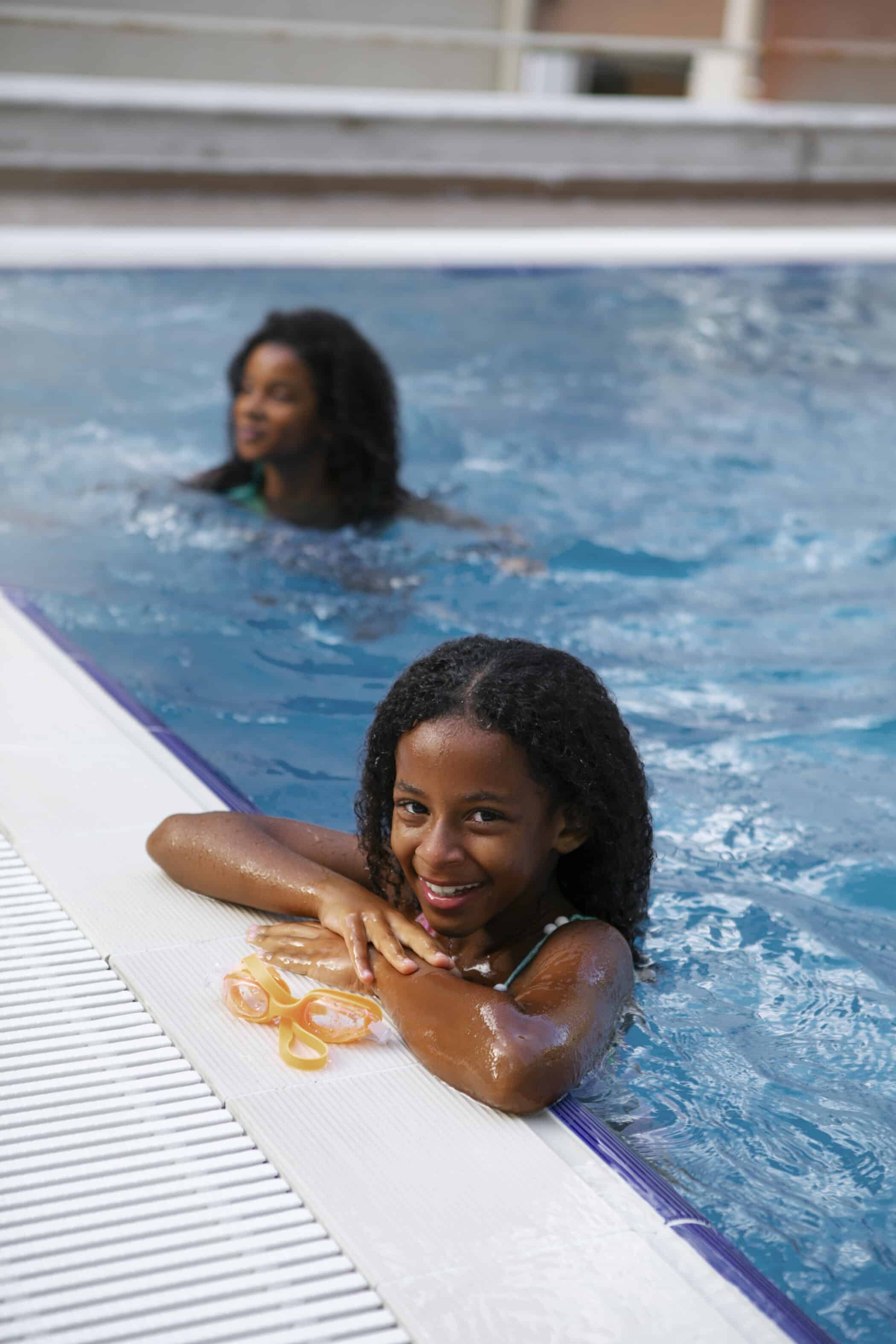 Girl in swimming pool. Family-friendly facilities. Learning to swim with sister.