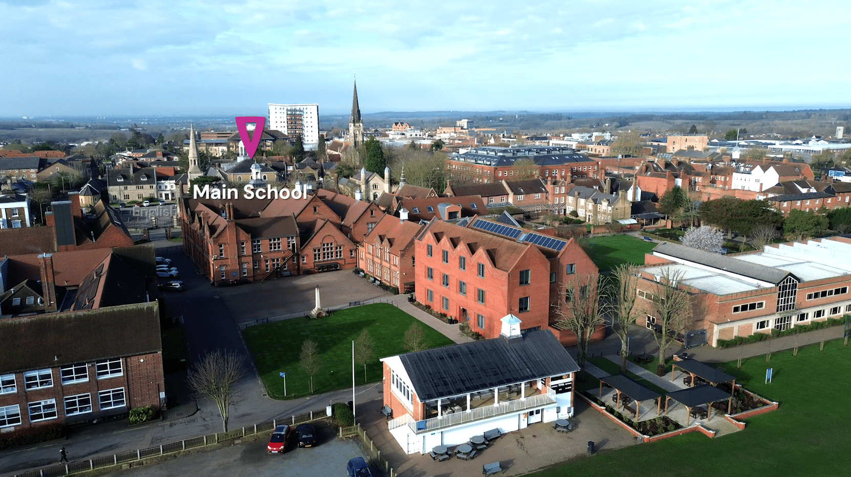Aerial view of a school campus with red-brick buildings, lawns, and sports areas; a digital marker points to the “Main School.” Experience Boarding at Brentwood amid scenic surroundings and a vibrant town under a partly cloudy sky.