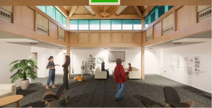 A spacious, modern lounge with large windows, wooden accents, and people talking or relaxing on chairs and sofas. A green exit sign hangs from the ceiling, and a large potted plant is in the corner.