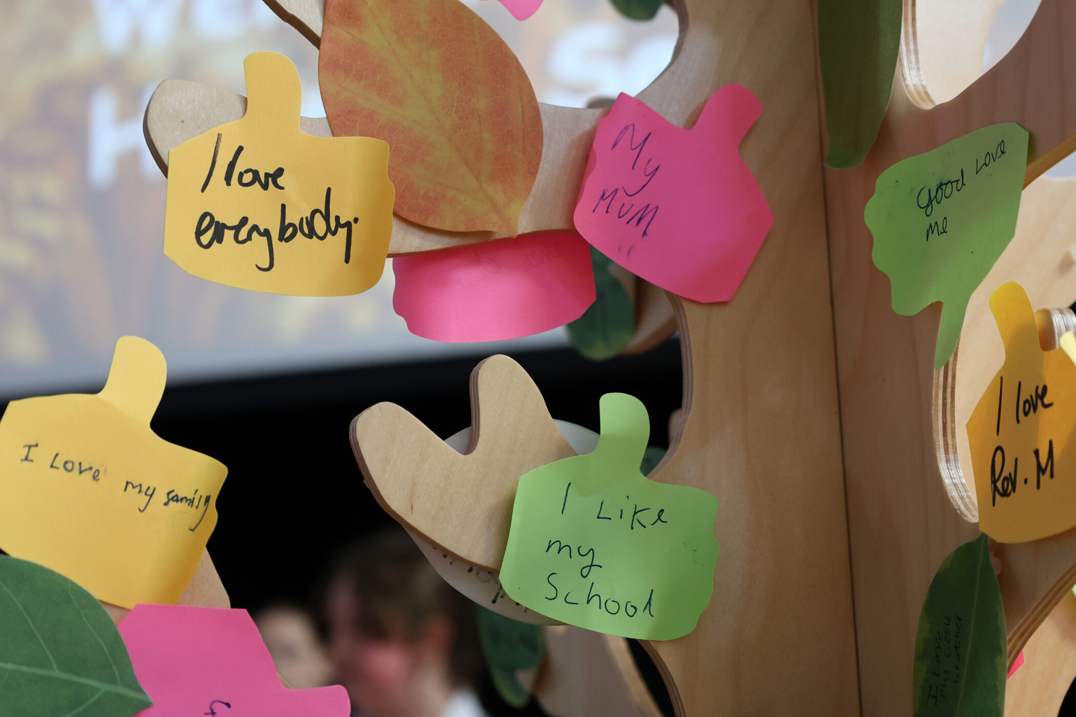 A wooden cut-out tree decorated with colourful adhesive notes featuring handwritten messages of appreciation.